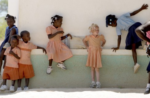 HAITI, Isla de la Laganave, School childrem in uniform playing, including an Albino girl.