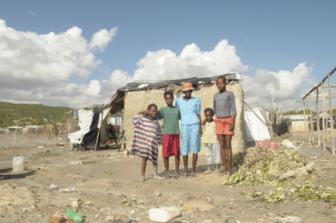 HAITI, Isla de la Laganave, family stood outside their shack in slum area.