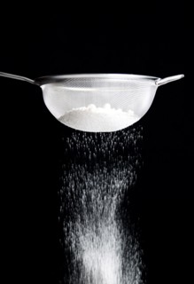 Food, Baking, Flour, White plain flour being siifted through a sieve against a black background.
