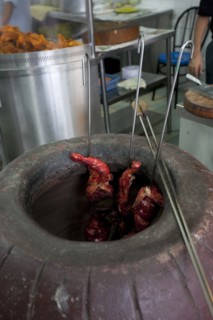 Malaysia, Kuala Lumpur, Skewered Tandoori chicken while being baked inside a Tandoor Oven at the