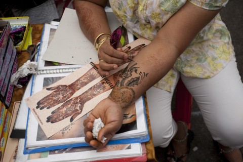 Singapore, Little India, Thieves MArket, Woman painting Henna Tattoo on her own arm whilst leaning