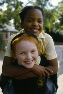 England, West Midlands, Birmingham, Smiling young girls in school playground with the white girl
