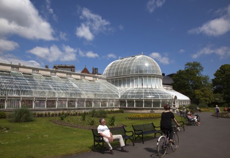 Ireland, Northern, Belfast, Botanic Gardens with people sat on benches outside the Palm House next