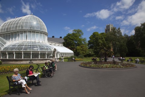 Ireland, Northern, Belfast, Botanic Gardens with people sat on benches outside the Palm House next