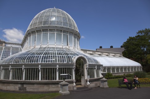 Ireland, Northern, Belfast, Botanic Gardens with people sat on benches outside the Palm House next