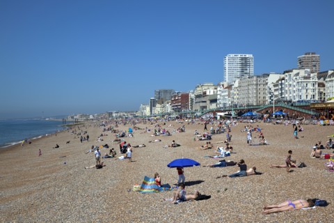 England, East Sussex, Brighton, people sunbathing on the pebble beach.