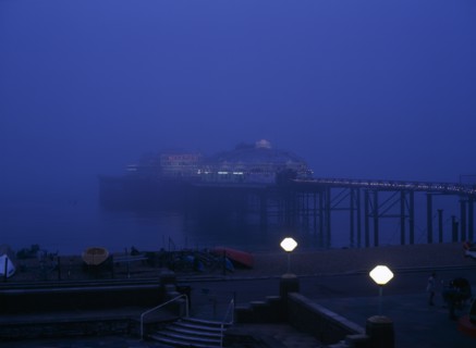 Brighton, East Sussex, England. The West Pier illuminated in evening light with mist on the sea