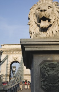 Budapest, Pest County, Hungary. Lion statue on Szechenyi Chain Bridge or Memory Bridge with passing