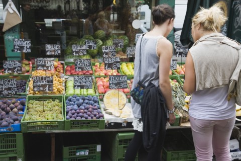 Vienna, Austria. The Naschmarkt. Two young women choosing fresh fruit from display including figs