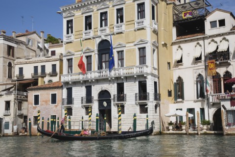 Venice, Veneto, Italy. Gondolier steers gondola from Rialto bridge along Grand Canal with Venice