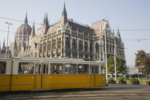 Budapest, Pest County, Hungary. Yellow tram passing the Parliament Building. Hungary Hungarian
