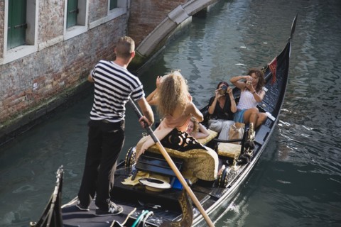 Venice, Veneto, Italy. Centro Storico Gondolier steering gondola along canal as models are