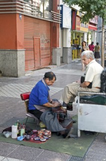 Santiago, Chile. Elderly man at street shoe shine in downtown shopping area piles of shoe polish