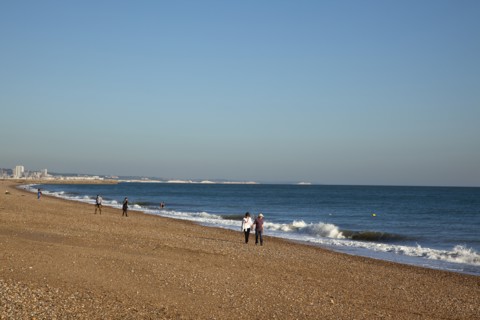Shoreham-by-Sea, West Sussex, England. People walking along the waters edge on Shoreham beach.