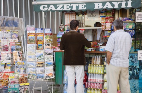 Istanbul, Turkey. Sultanahmet. Customers at newspaper kiosk with magazine stand and display of maps