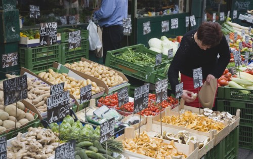 Vienna, Austria. The Naschmarkt. Stallholder selecting mushrooms from display of fresh produce also