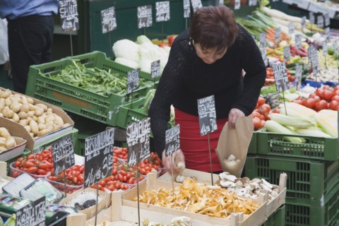 Vienna, Austria. The Naschmarkt. Stallholder selecting mushrooms from display of fresh produce also