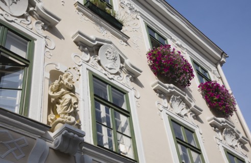 Vienna, Austria. Pastel painted building facade with religious statue and colourful window boxes of