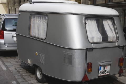 Vienna, Austria. Neubau District. Car towing vintage caravan along cobbled road. Austria Austrian