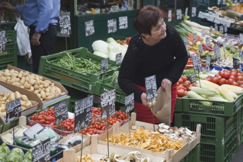 Vienna, Austria. The Naschmarkt. Stallholder selecting mushrooms from display of fresh produce also