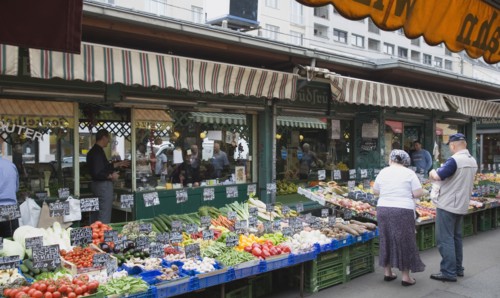 Vienna, Austria. The Naschmarkt. Customers at fresh produce stall with display including peppers