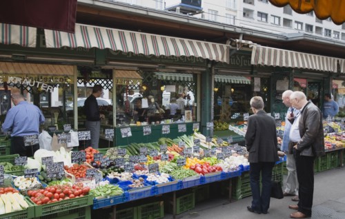 Vienna, Austria. The Naschmarkt. Customers at fresh produce stall looking at display that includes