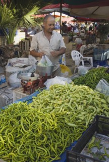 Kusadasi, Aydin Province, Turkey. Turkish stallholder selling green chilis under shade in town