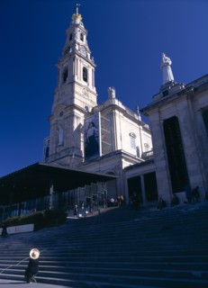 Fatima, Beira Litoral, Portugal. Woman wearing hat seated by steps beneath the church Female Women
