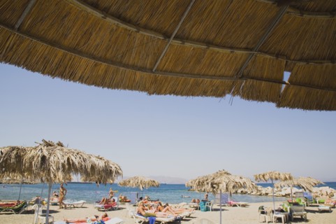 Kos, Dodecanese Islands, Greece. People sunbathing on beach outside Kos Town part framed by
