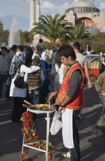Istanbul, Turkey. Sultanahmet Man standing at food stall in front of Hagia Sophia with crowds of