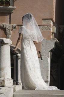 Venice, Veneto, Italy. Bride in white wedding dress and veil standing on canal bridge in late