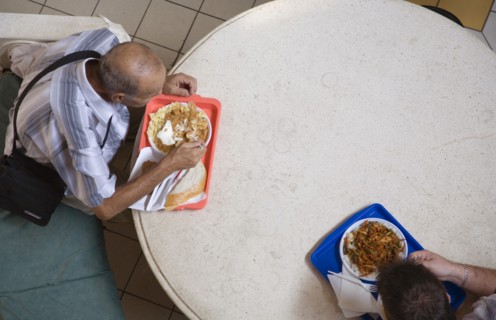 Budapest, Pest County, Hungary. Looking down on two men having lunchtime meal seated at circular