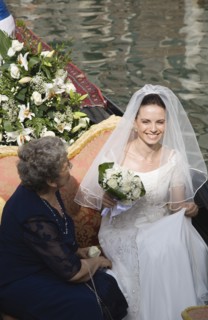 Venice, Veneto, Italy. Smiling bride in wedding dress and veil carrying bouquet of white roses