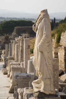 Selcuk, Izmir Province, Turkey. Ephesus. Headless statue on plinth in line of ruined pillars and