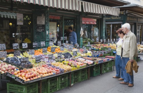Vienna, Austria. The Naschmarkt. Customers selecting fresh fruit from display on market stall that