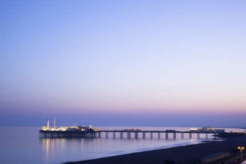 Brighton, East Sussex, England. View of the pier at sunset from the seafront promenade in Kemptown.
