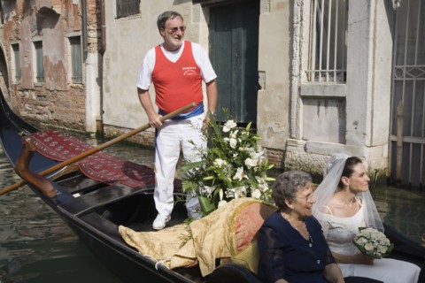Venice, Veneto, Italy. Gondolier steering decorated gondola carring bride in wedding dress and veil