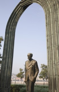 Budapest, Pest County, Hungary. Statue of standing man beneath arch beside the River Danube.