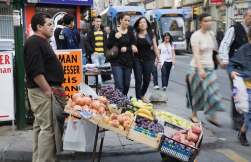 Istanbul, Turkey. Sultanahmet. Pedestrians pass fresh fruit stall with male vendor on busy street
