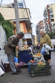 Albania, Tirane, Tirana, A street vendor using hand held set of scales to weigh fruit for elderly