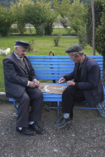 Albania, Berat, Two elderly men playing dominos on park bench.
