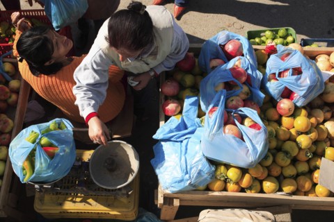 Albania, Tirane, Tirana, Looking down on street vendor using set of scales to weigh chillis at