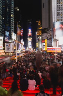 USA, New York, New York City, Manhattan  People sitting on lit red steps or walking at night in