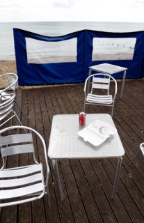 England, West Sussex, Bognor Regis, Empty aluminium chairs and tables on wooden decking behind a