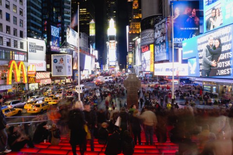 USA, New York, New York City, Manhattan  People sitting on lit red steps or walking at night in