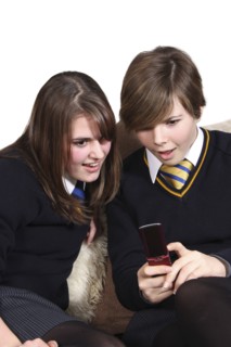 Children, Teenagers, Girls, Teenage girls in school uniform texting on a mobile phone.