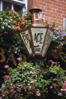 Ireland, County Dublin, Dublin City, Old copper gas lamp and flowers in hanging baskets outside the