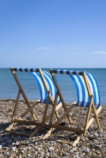 England, West Sussex, Bognor Regis, Two blue and white deck chair on the shingle pebble beach