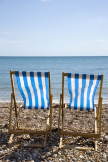 England, West Sussex, Bognor Regis, Two blue and white deck chair on the shingle pebble beach