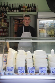 Albania, Tirane, Tirana, Cheese shop with young male vendor standing behind counter in the Avni